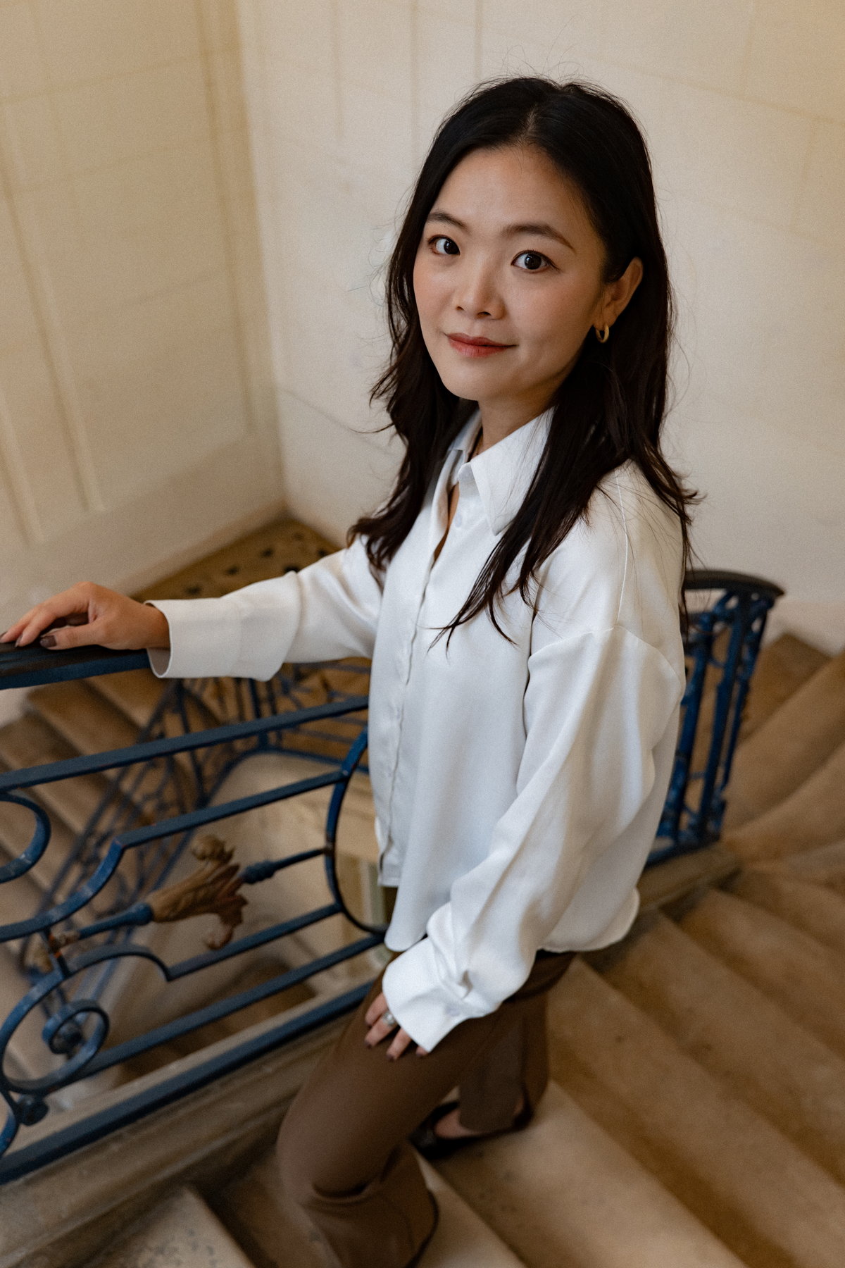 Nina Xu on a stairwell landing beside a blue wrought-iron banister
